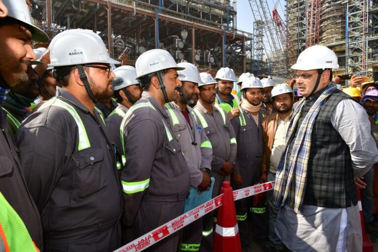 Team of workers in safety helmets and hi-vis vests at a site
